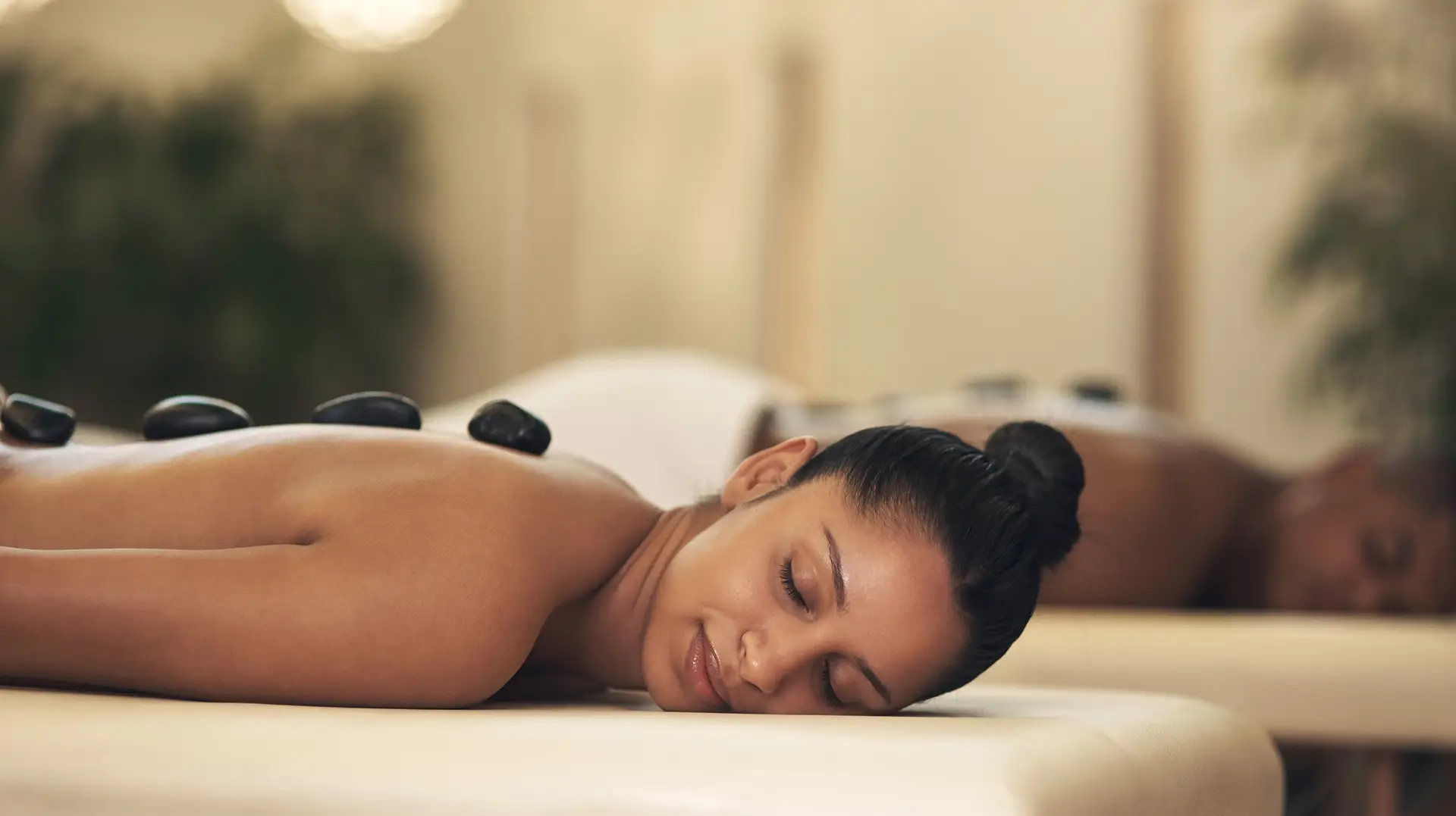 Woman receiving hot stone massage, relaxing ambiance.