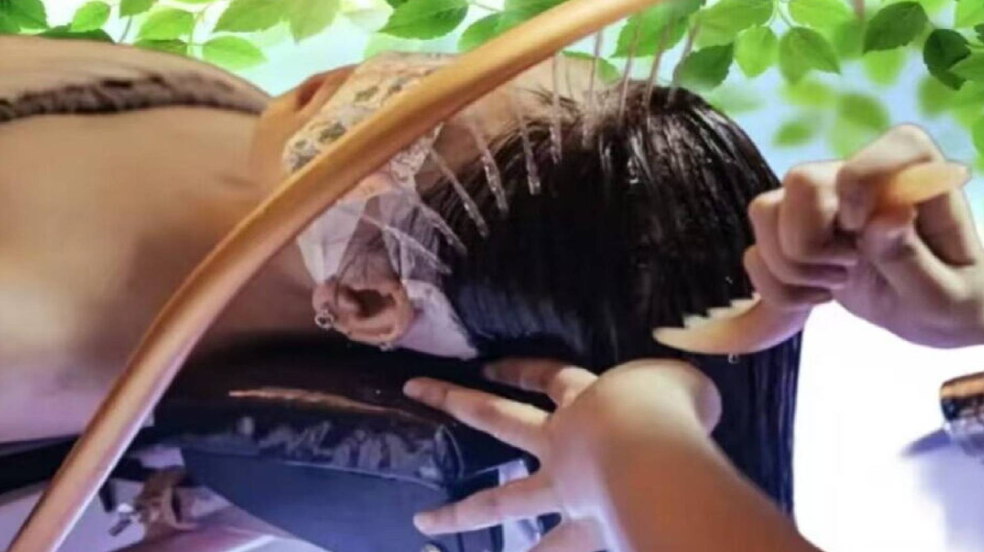Person lying down with hands over their face, wearing a hat and dark clothing.